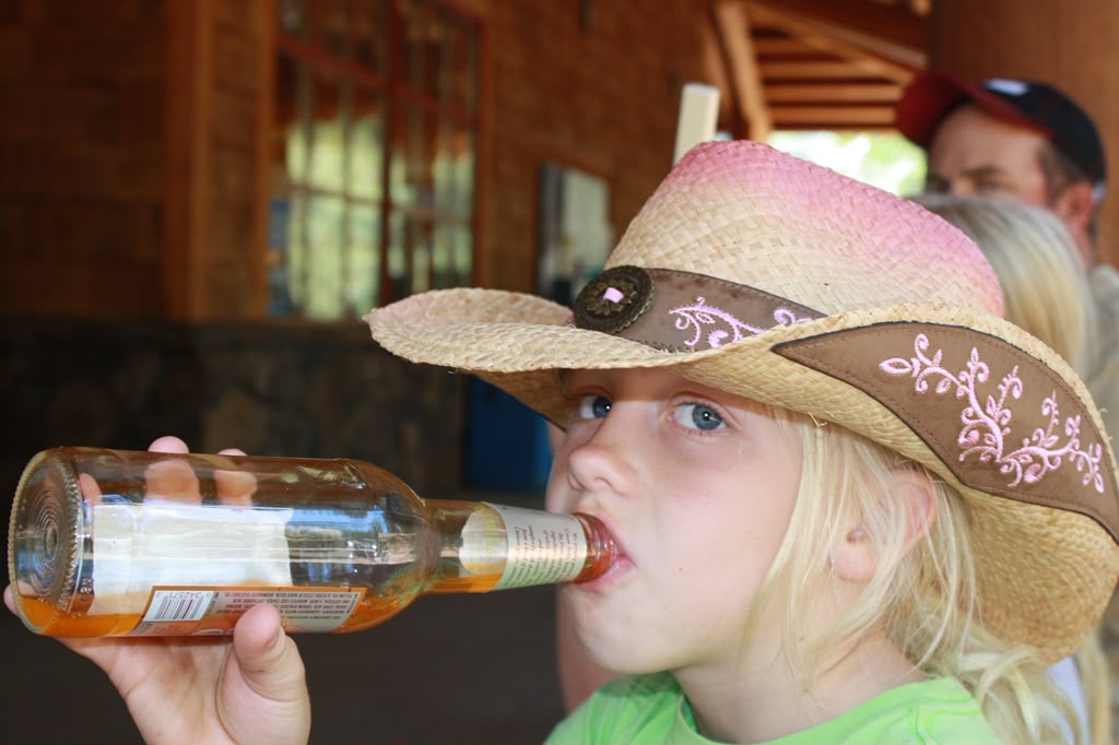 Young Olivia in a pink straw cowboy hat, drinking from a bottle
